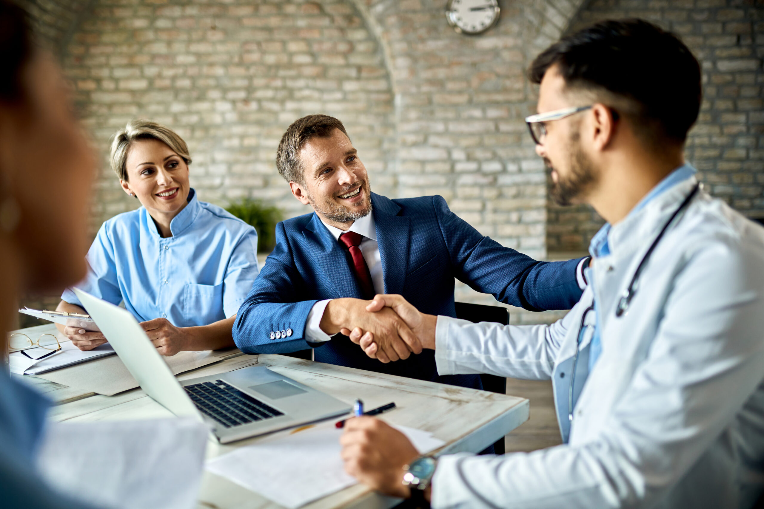 Happy businessman handshaking with a doctor on a meeting in the